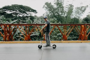 A man using a scooter in broad daylight.