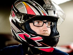A rider with glasses wears his helmet as a very important protective gear while enjoying the race. 