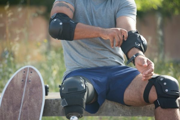Man sitting, putting on knee and elbow pads 