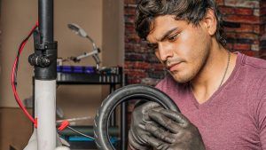 A man in the process of maintaining his waterproof scooter, emphasizing its waterproof design. Waterproof features contribute to an easy maintenance.