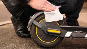 A man effortlessly cleans his waterproof scooter using wipes. Waterproof features contribute to an easy maintenance. 
