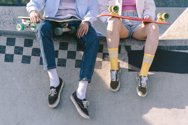 skaters with black shoes are sitting on a skate ramp featuring their shoes