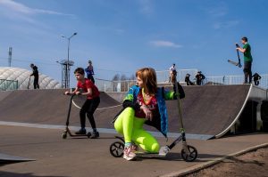 Kids doing stunts outdoors with stunt scooter. Their playful movements with scooter reflect the joy and excitement of this active, adventurous playtime. 