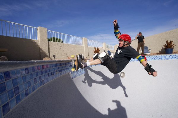 A man with complete protective gear is doing a trick during a bright day.