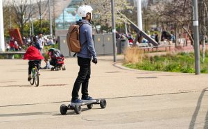 A skater is safely riding his electric skateboard 