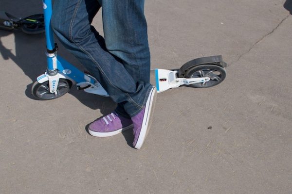 A child's feet next to a scooter