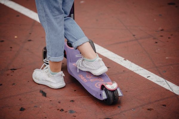 A child with one foot on a purple scooter