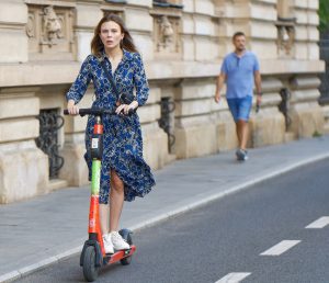 This woman is enjoying her scooter ride. Scootering can be fun .