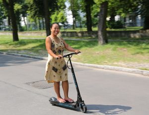 A woman scooting freely around the city. Scooter is fun.