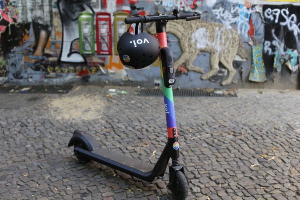Scooter with a black helmet resting on the handlebar parked on a cobblestone street