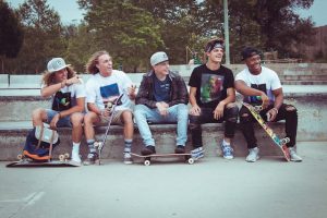 A group of teenagers holding their boards while experiencing the positive impact of board riding on their psychological and physical well-being.