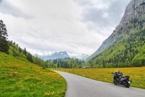 A black scooter rides across the green mountains ready for new expedition.