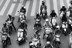 People on scooters in the street wearing helmets for safety exploration.