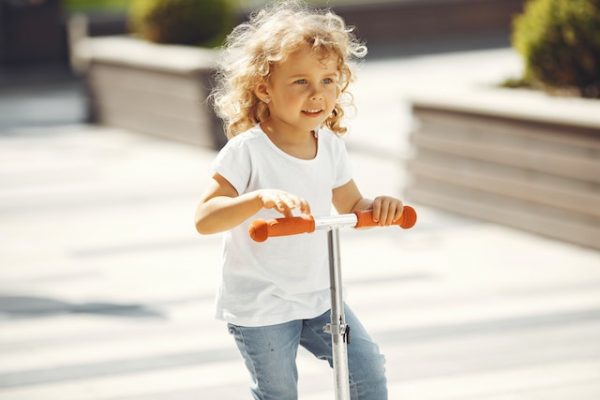 A young girl riding her scooter.