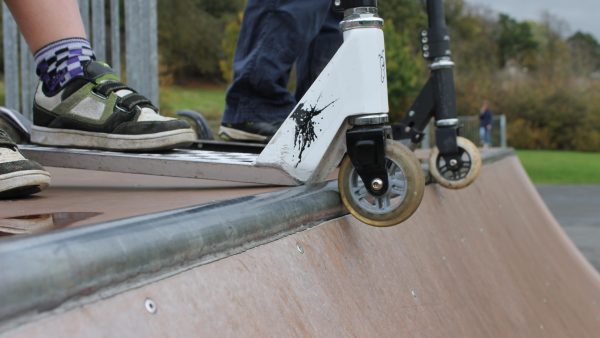 There are two scooters at the edge of the skating park. 