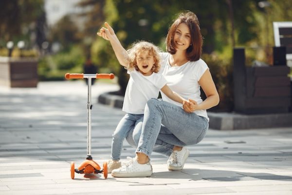 Mommy and daughter playing outside with a 3-wheeled kick scooter. Discover how this tool can help your child develop spatial awareness.