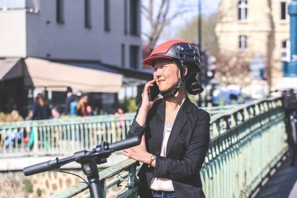 A lady wearing scooter helmet while having a phone call.