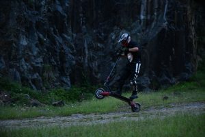 A man with a helmet practices advanced scooter tricks. 