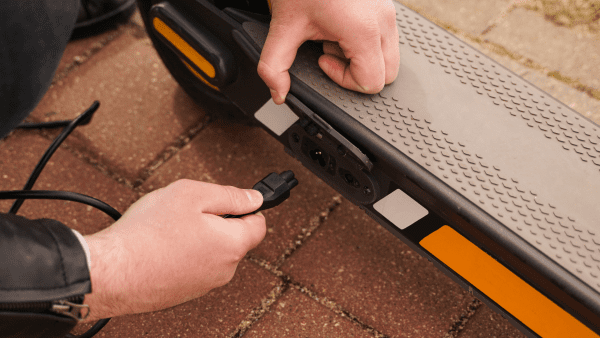 A man charging an electric scooter. 