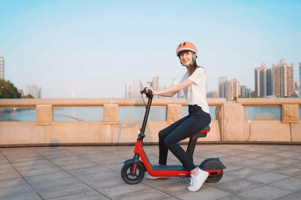 Electric Scooter Laws - A girl is sitting on her electric scooter with the city skyline in the background.