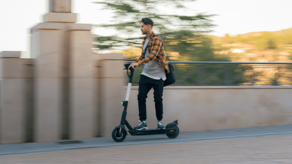 A man driving a scooter on the side road. The picture has a blurry effects. 