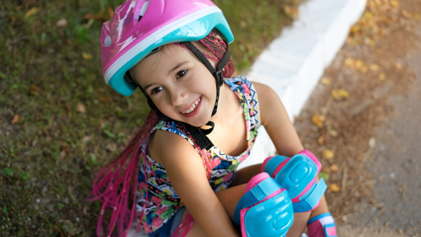 A picture of a little girl with safety gears (helmet, and knee pads)