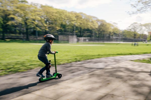 A boy riding his scooter while wearing all the protective equipment in a park on a very beautiful sunny day. It is important to keep your vehicle in top shape and know when it is time to change it for your security. 