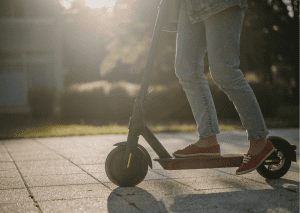 A close up shot of a person using a scooter on a sunny day.