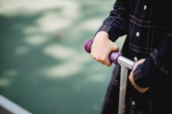 A close up of a child's hands holding a scooter