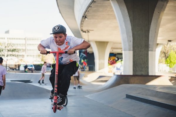 A boy jumping on a scooter