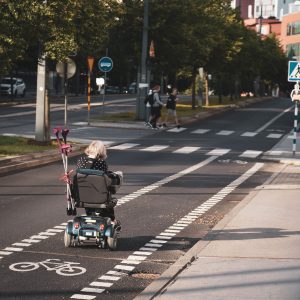 An elderly woman is riding a scooter.