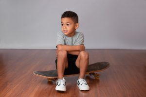 A cute and charming little boy is sitting on a board.