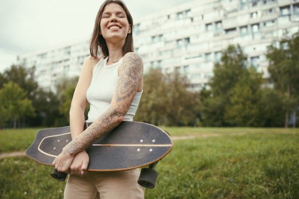 Girl holding a skateboard. Maintaining the skateboard is a must.