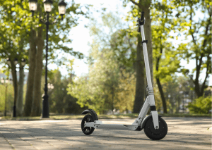 There's a scooter with minimalistic design on the road. There are also trees in the background. 