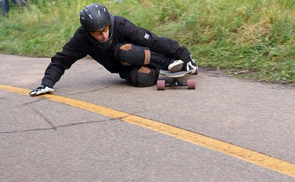 A man is skateboarding while wearing wrist guards. A safety guide.