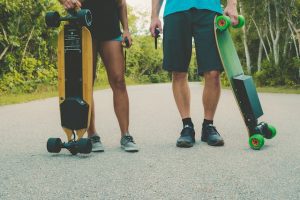 Two people holding electric skateboard.
