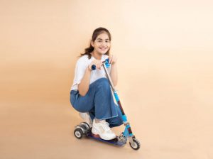 A girl on her blue scooter is smiling