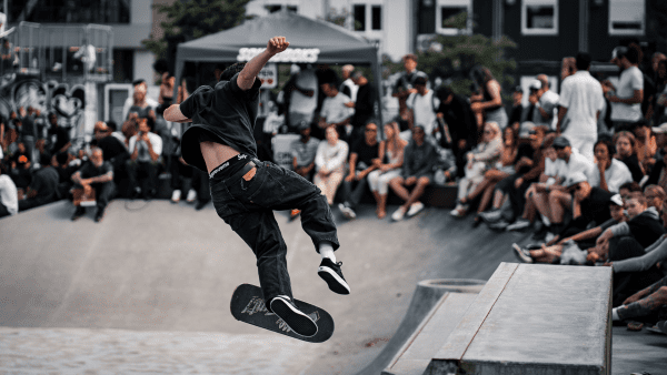 Skilled skateboarder performing impressive tricks in front of a captivated crowd, showcasing agility and talent in a dynamic and energetic skating exhibition.