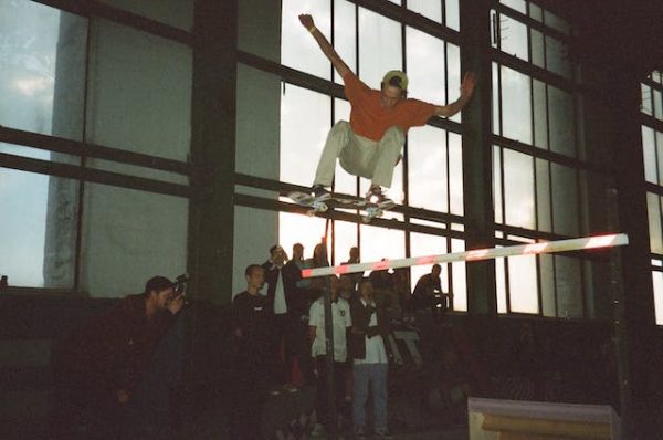 A skater confidently ride his skateboard in front of other skaters