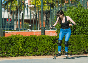 A woman practicing how to ride her board. She is also wearing some protective gear. It is really nice to keep them while riding the board to stay safe at all times.