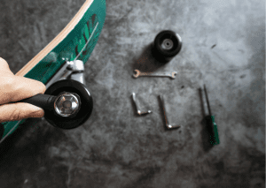 Person adding accessories to his green skateboard. 