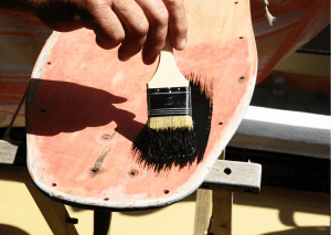 A person repairing his board by repainting it
