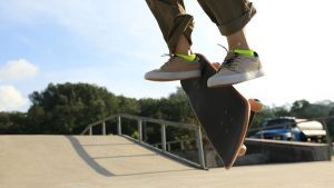 Close-up of a man's feet on a skateboard as he performs a turn trick. The man's skillful skating and precise turn on the skateboard highlight his mastery of the sport.