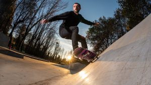 A confident man performing a twirling trick while skating at dawn. Mastering skate riding and perfecting the turn trick is crucial. 