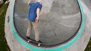 An elderly man demonstrates a skateboard turning trick. Discover how to execute turn tricks on a skateboard, just like the man at the skate park. His expertise on the skateboard, executing a flawless turn trick at the skate park, serves as inspiration for those eager to learn the art of skating.