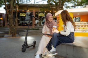 A scooter is parked beside two women talking.