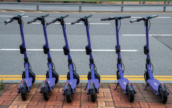 Six blue scooter wheels are parked beside the highway for scooter viewing promotion.