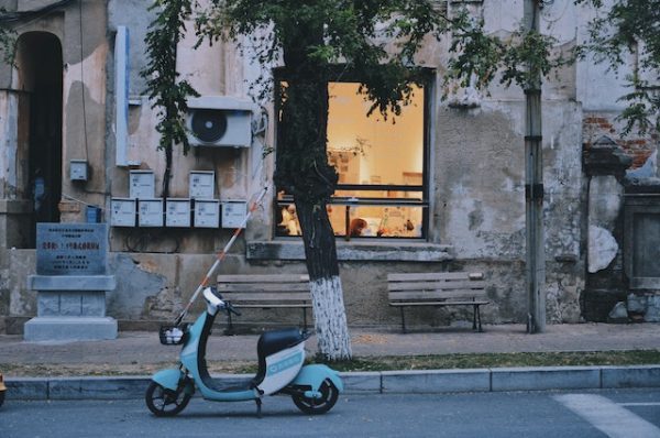 An electric scooter with seat parked in front of the house. 