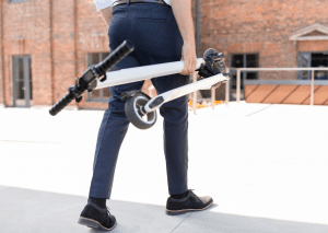 A person effortlessly holding a white foldable scooter.