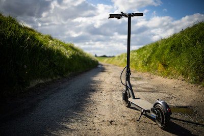 electric scooter that can be used for hills photographed in a rough terrain surrounded by grasses